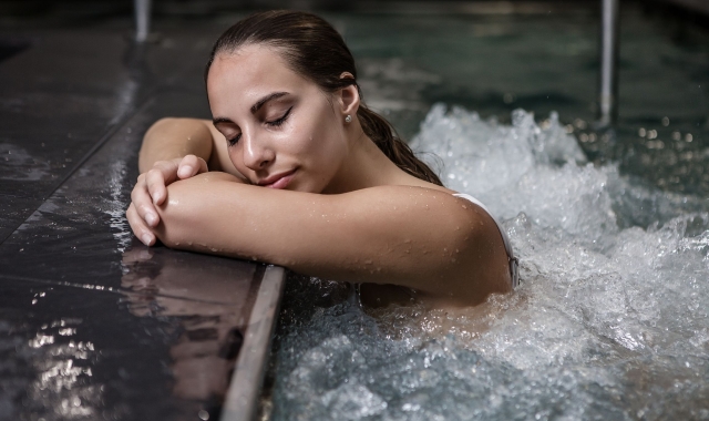 a woman in a pool leaning against the side of the pool with her eyes closed