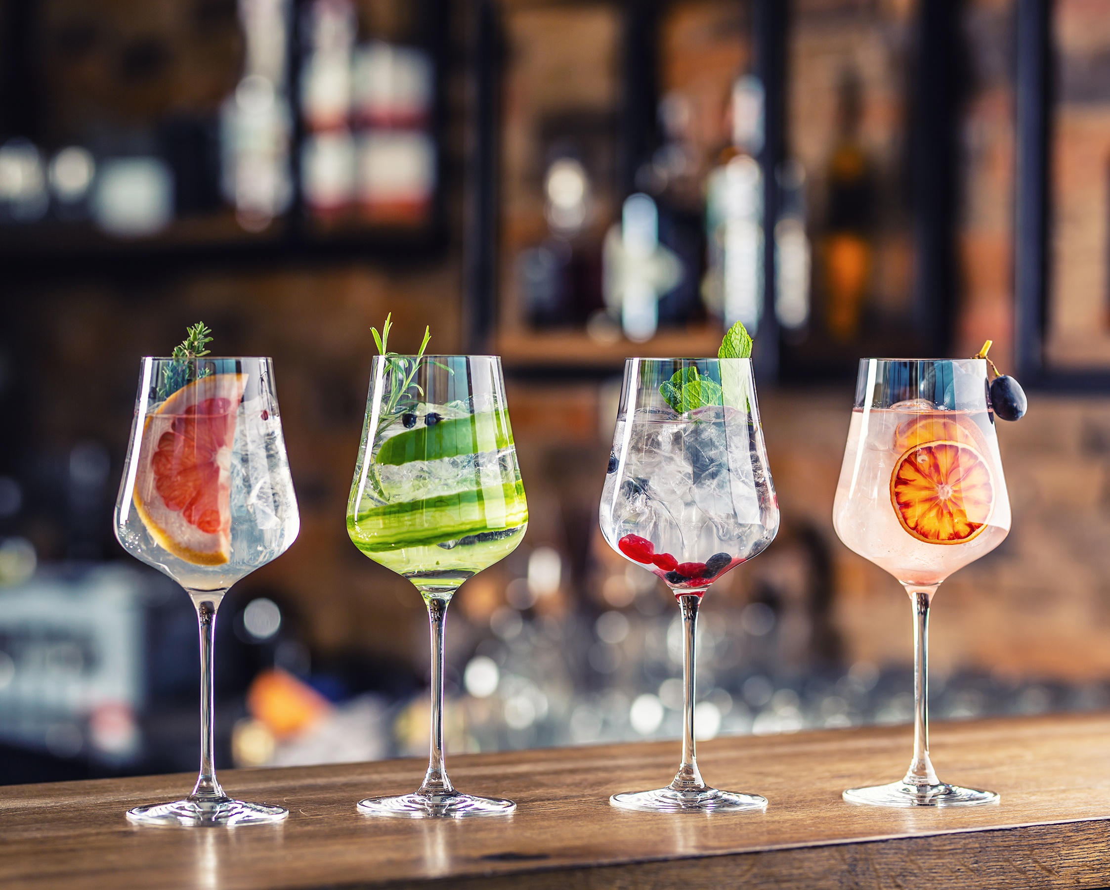 a line up of four cocktails on the counter top of the bar