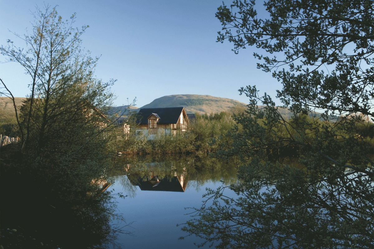 houses sitting behind a small body of water with mountains in the background