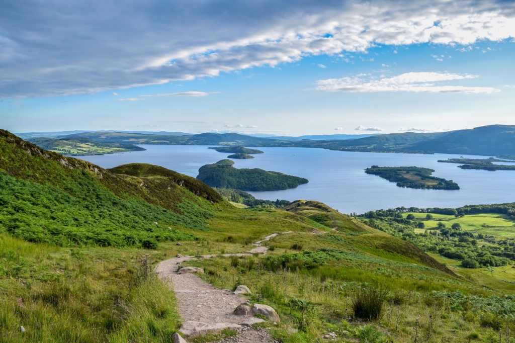 a trail leading down the side of a hill overlooking the water and islands