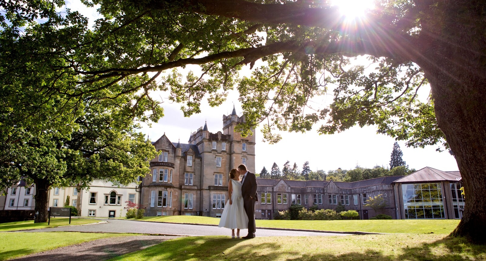 A bride and groom kissing under a tree at the Cameron House.