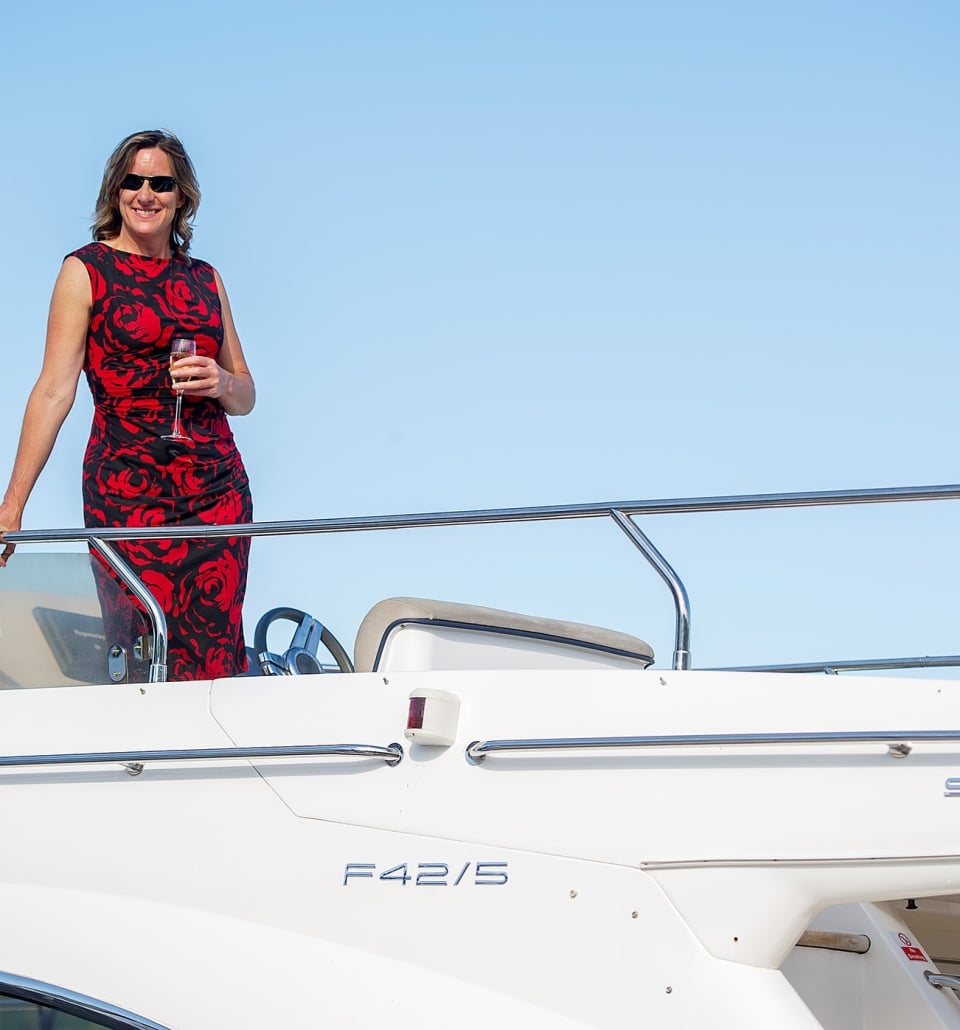 a woman standing on the top level of a boat wearing a elegant floral dress