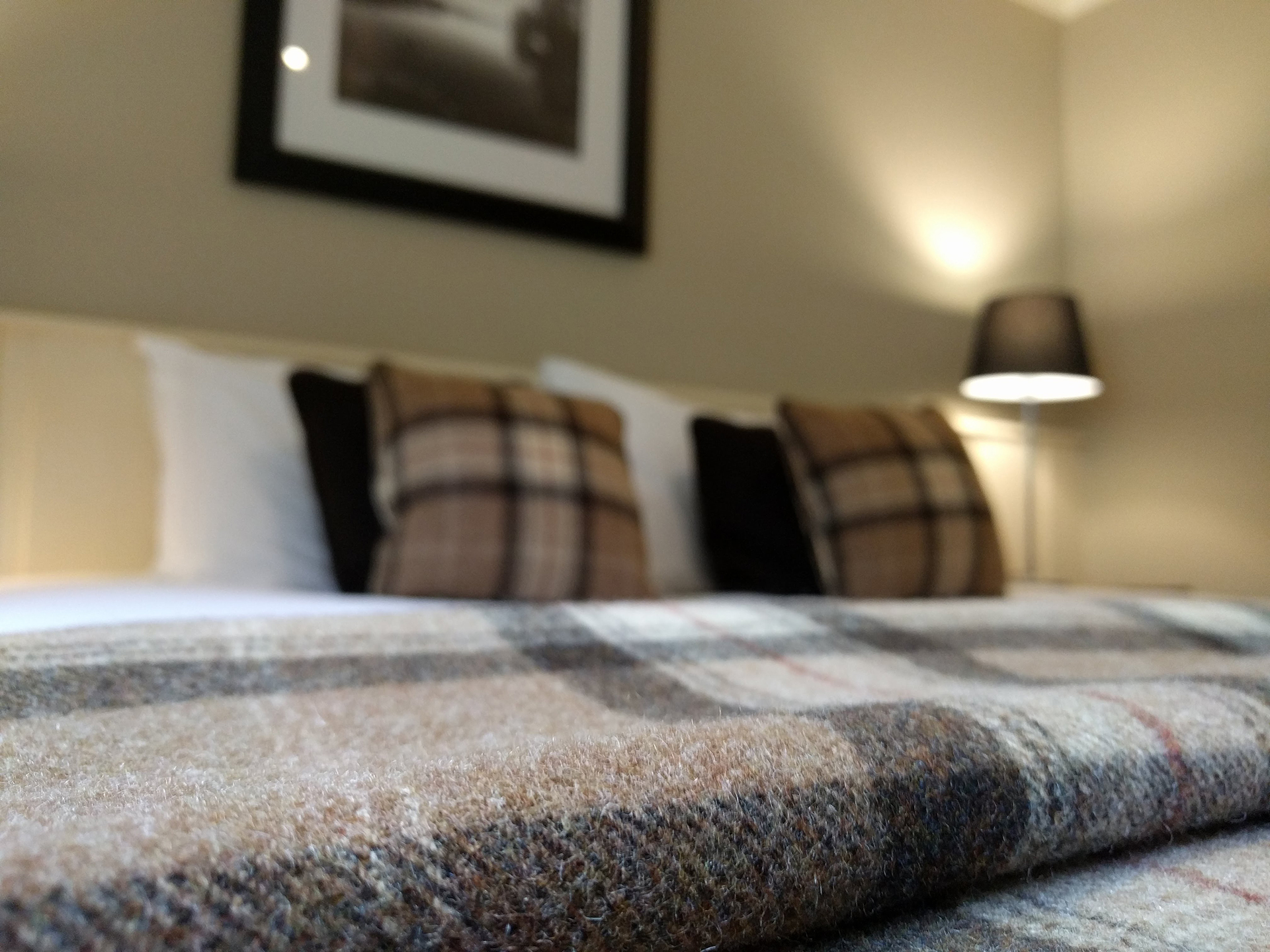 A warm wool tartan blanket on a hotel bed.