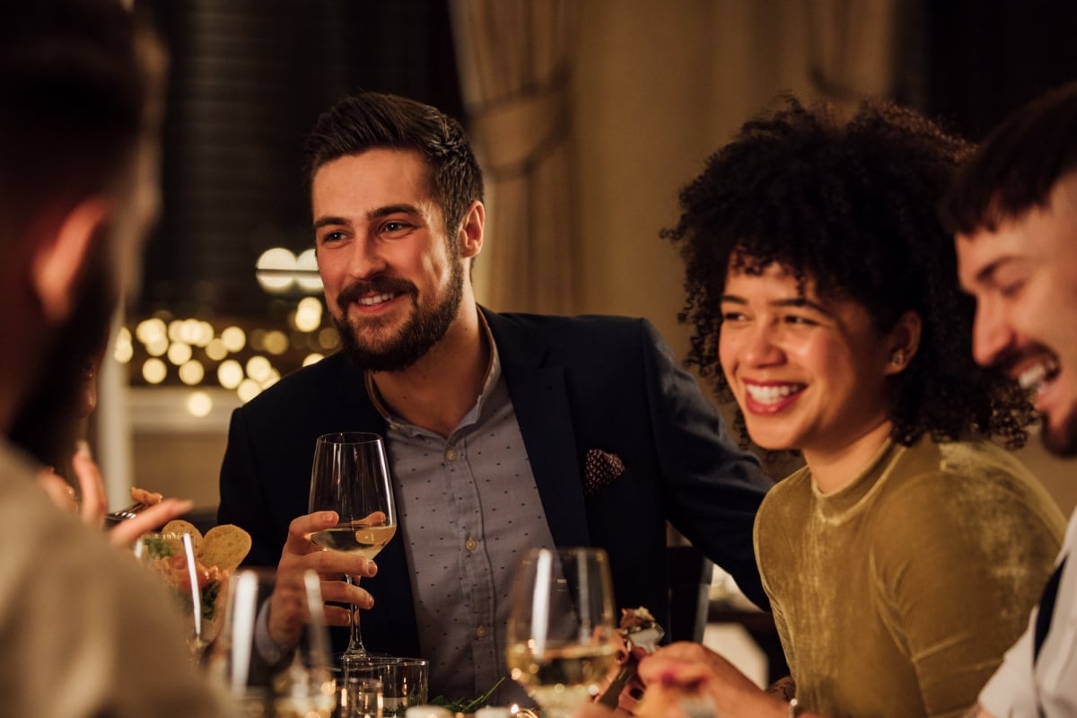 Friends gathered around a table enjoying dinner and drinks.