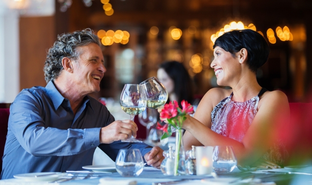 A man and woman celebrating over dinner and enjoying glasses of wine.