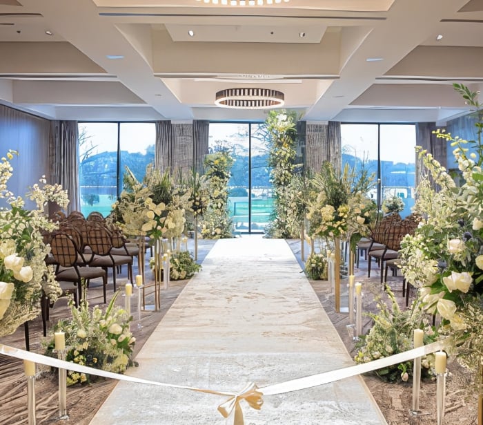 An elegant wedding ceremony aisle with white flowers lining either side of the aisle.