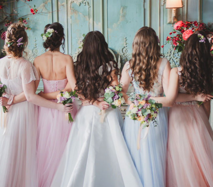 A bride and her bridesmaids with their backs turned.