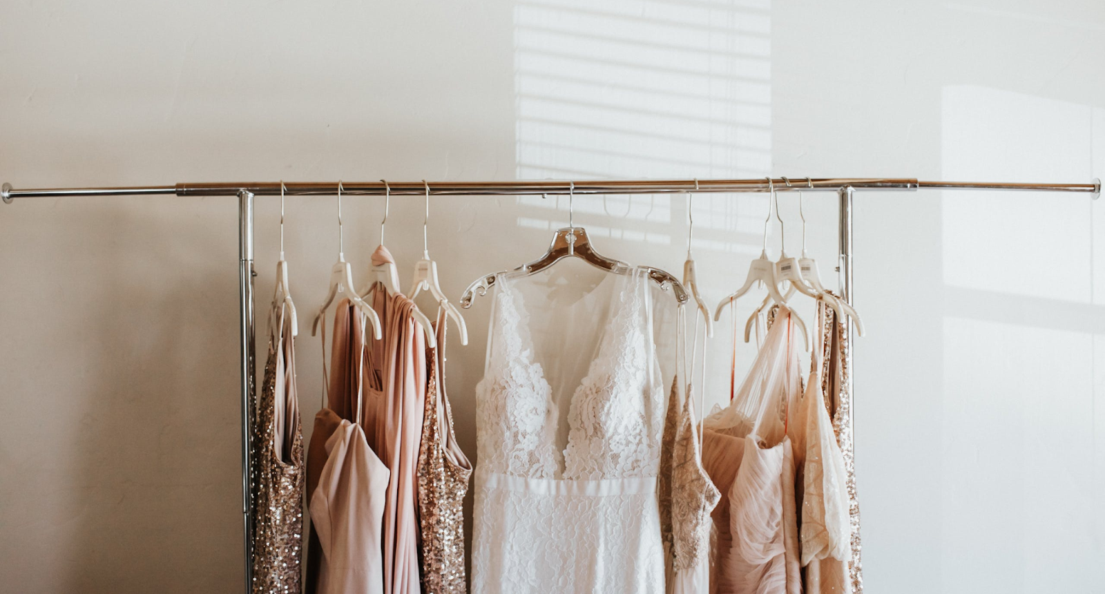 Bride and bridesmaid dresses hanging on a rack.