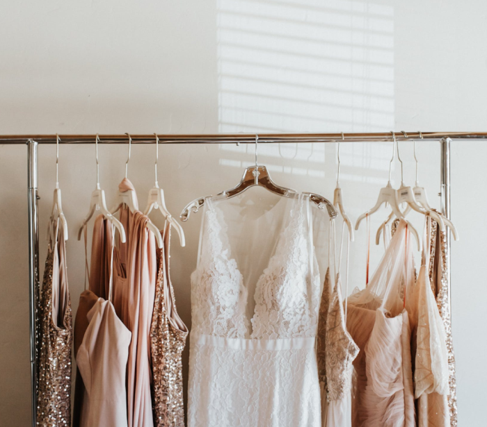 Bride and bridesmaid dresses hanging on a rack.