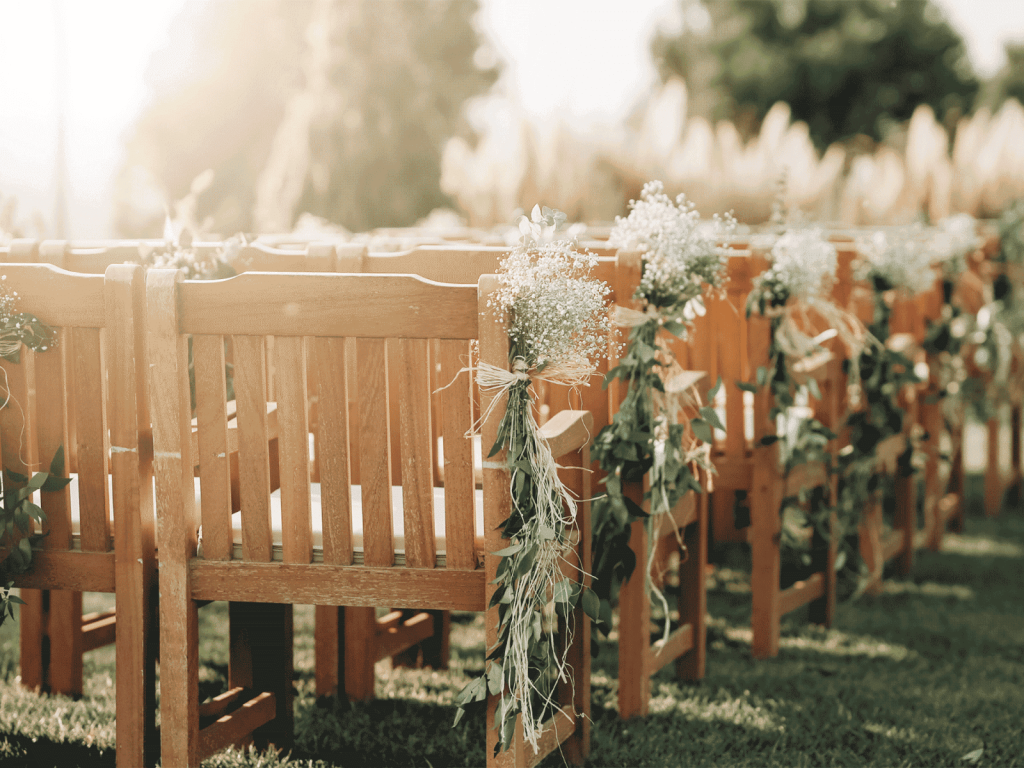 Wedding aisle seats, with wedding flowers hanging on the sides. 