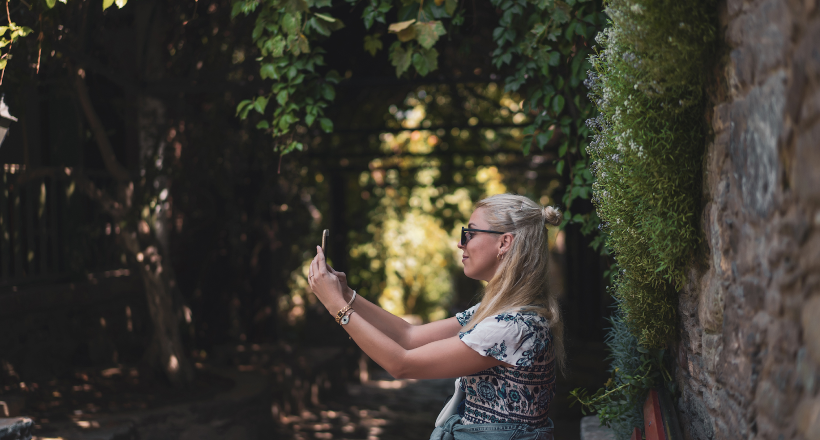 A blonde woman taking a selfie in a forest.